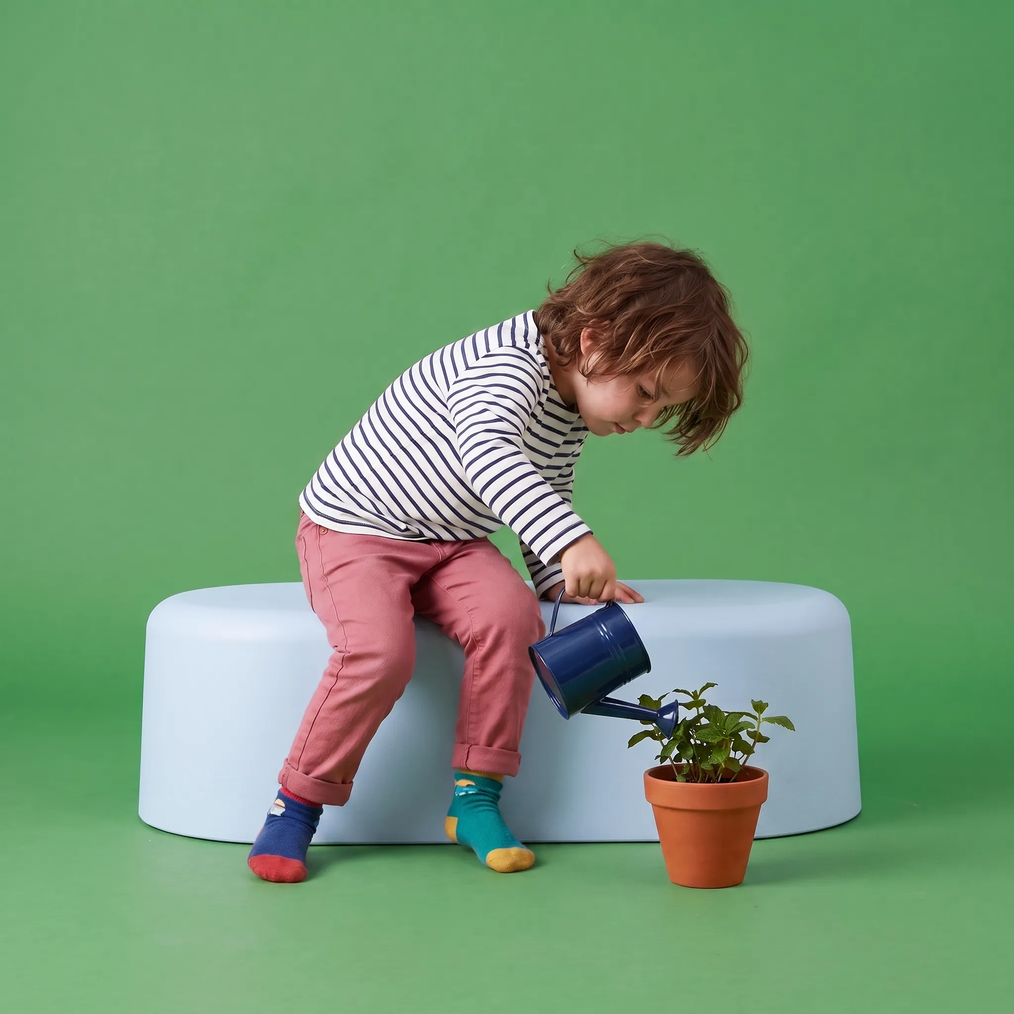 A child watering a plant on a green background